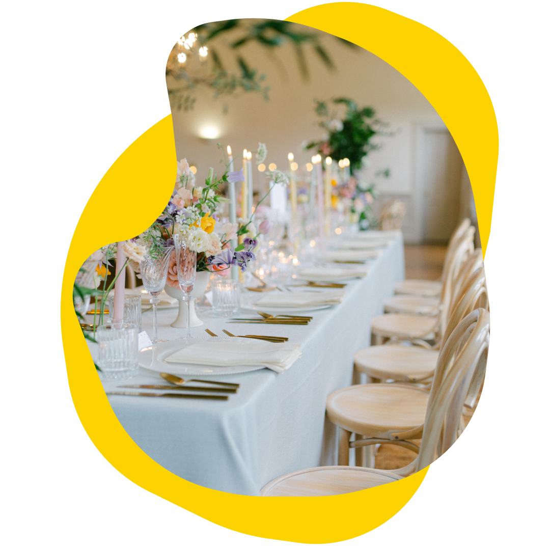 Long table set for a formal event with floral centerpieces, candles, and place settings.