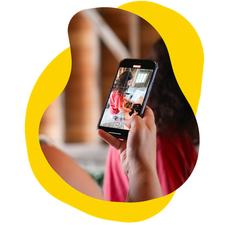 Person holds a smartphone, taking a video. The screen shows a scene with a person.
