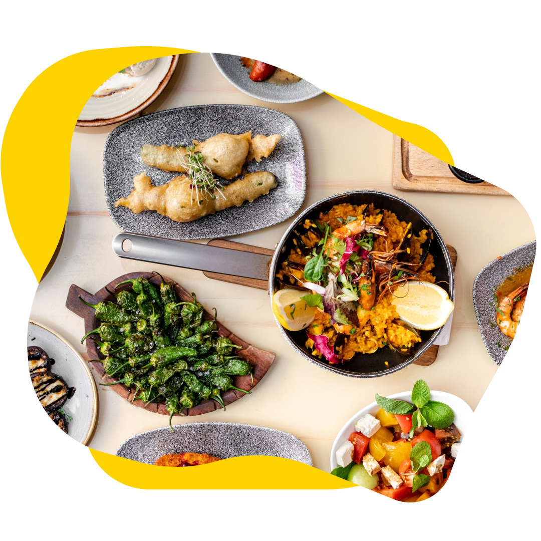 Overhead shot of various plates of food on a table, including couscous, salad, and fried items.