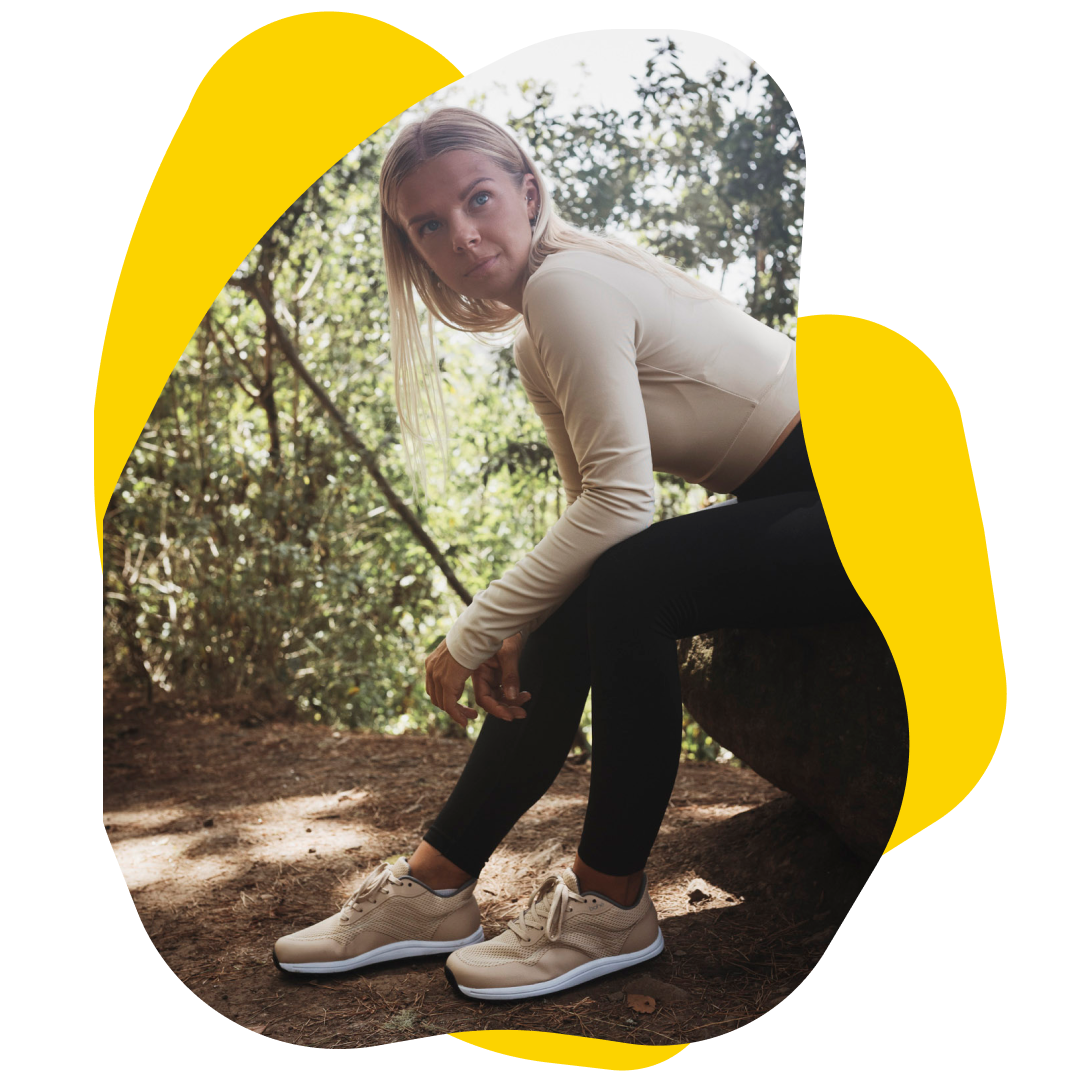 Woman in activewear sitting on a log outdoors, looking at the viewer.