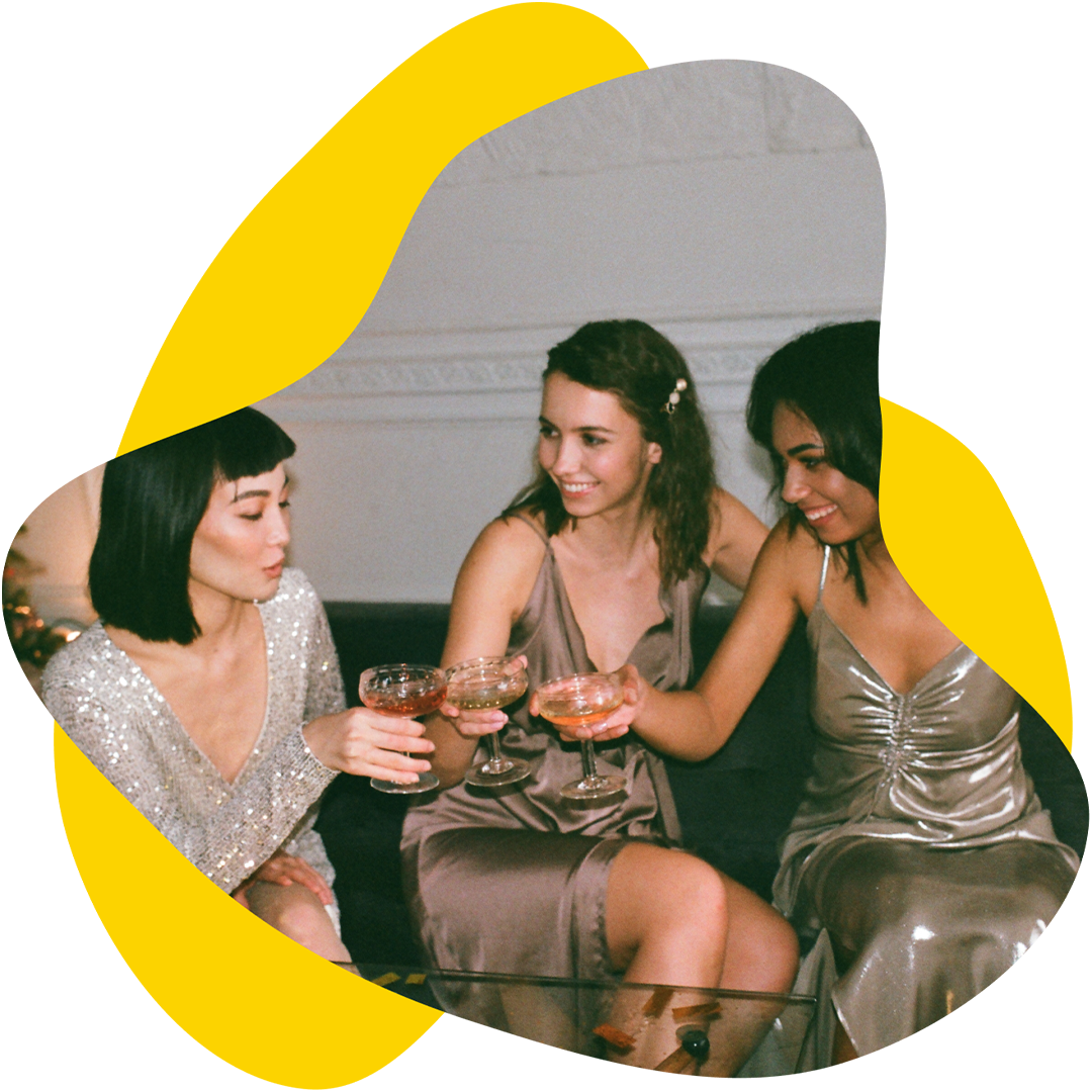 Three people in formal attire toasting drinks in a dimly lit room.