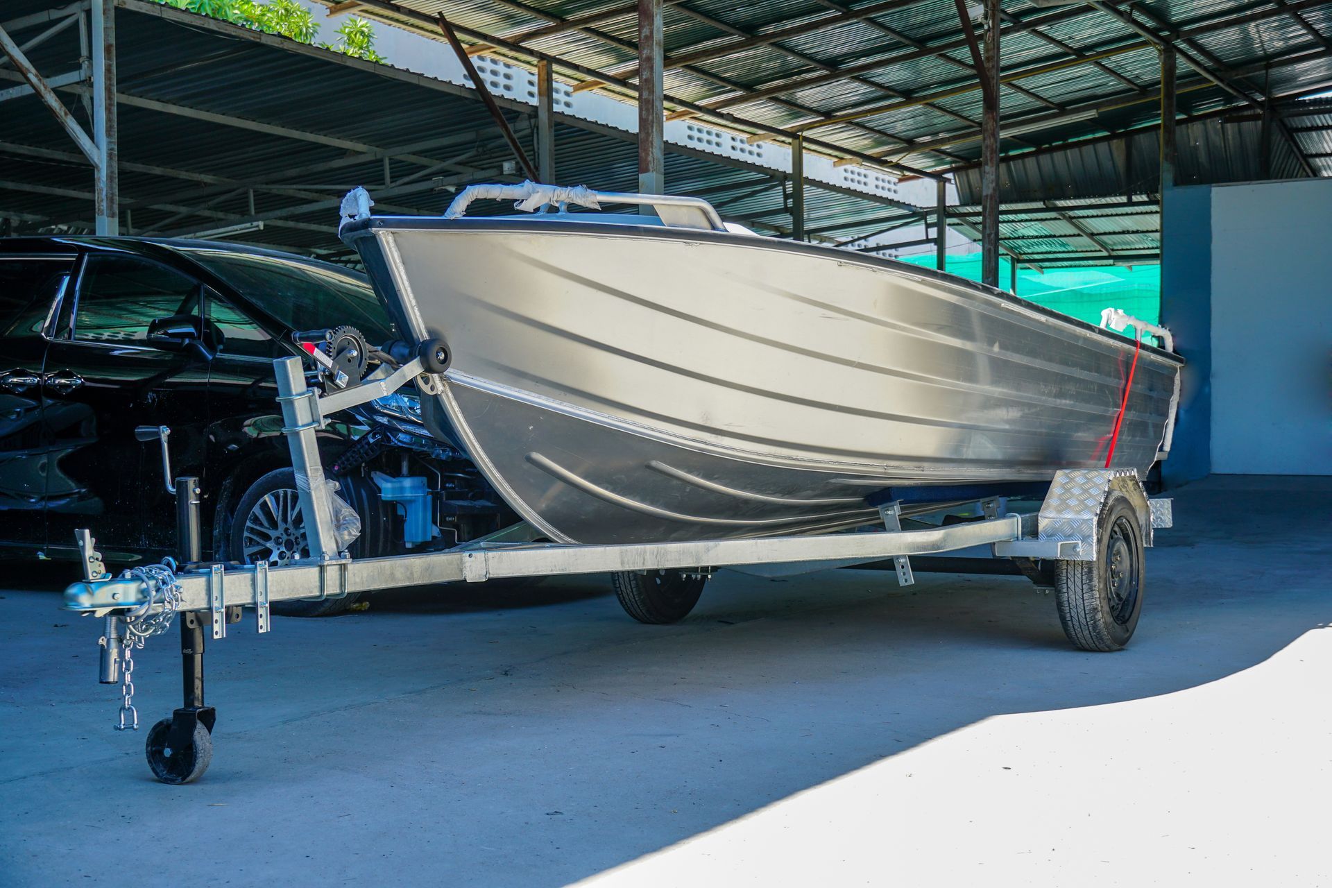 Small silver boat on a trailer inside a covered warehouse or showroom