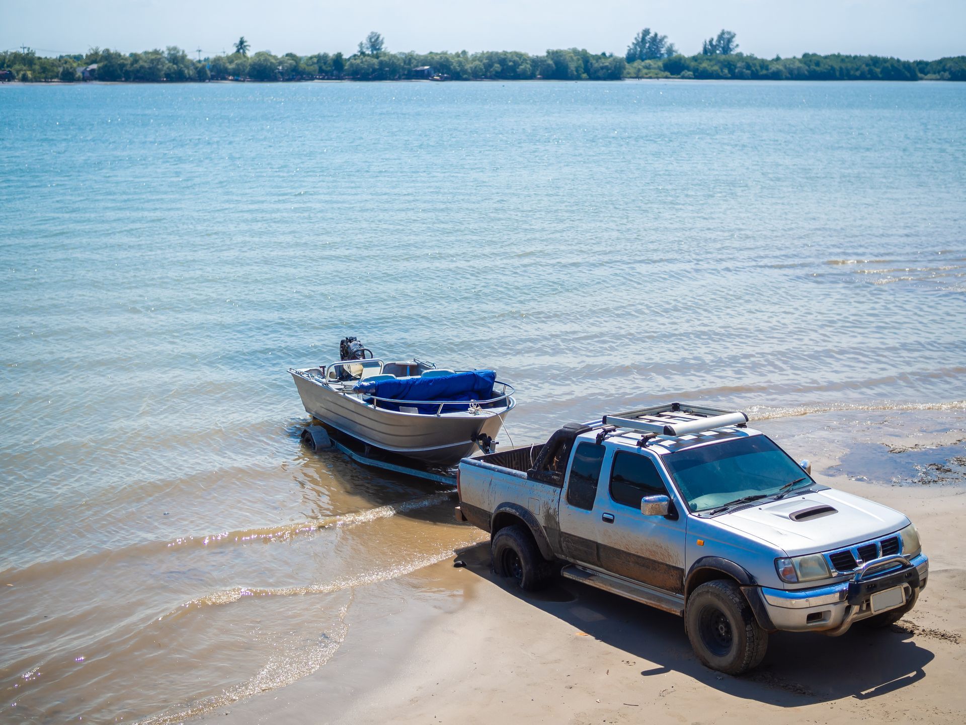 Pickup truck towing a boat from shallow water at a lakeshore