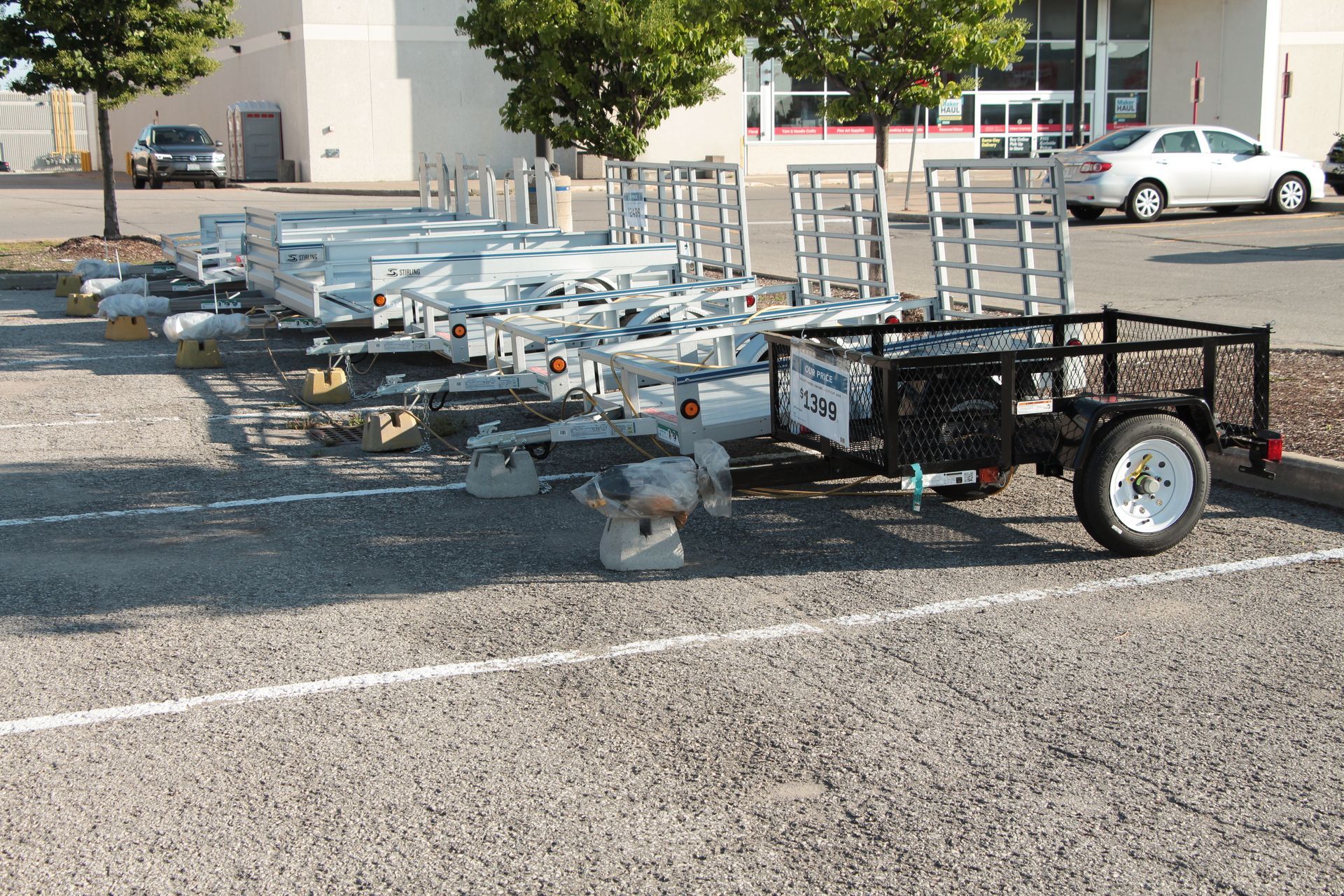 Flatbed trailer loaded with metal cart frames parked in a lot on a sunny day