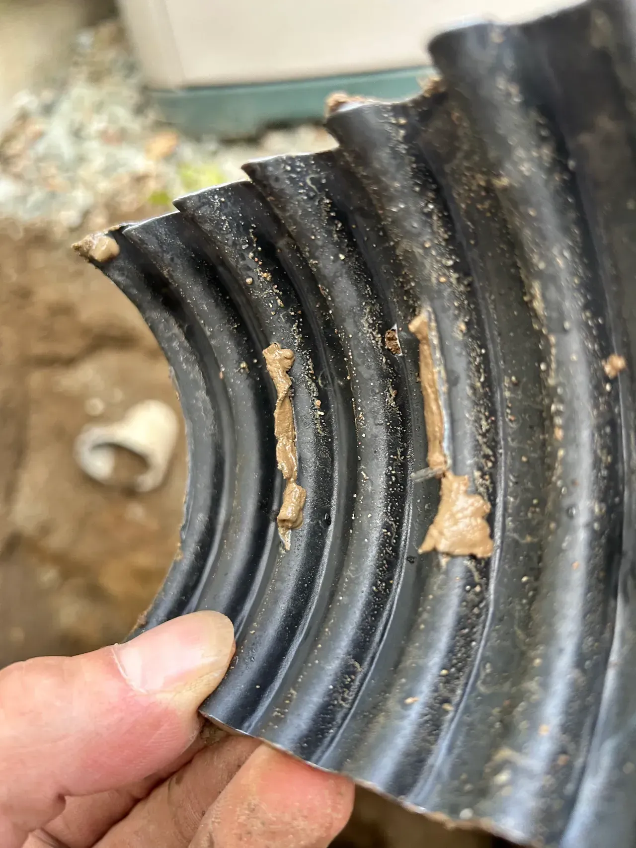 Thick, dense, clay soil with deposits and small rocks that clogs drain tile pipes