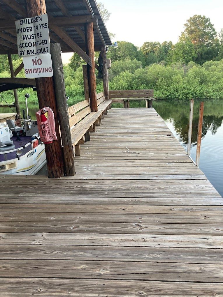 A wooden dock with a boat and a sign on it.