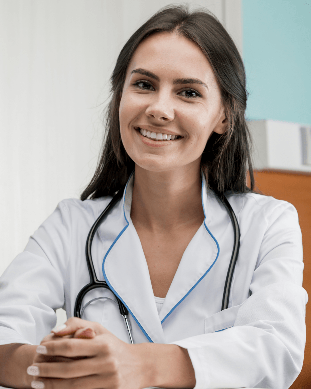 Médico sorridente de jaleco branco e estetoscópio, sentado no consultório de uma clínica.