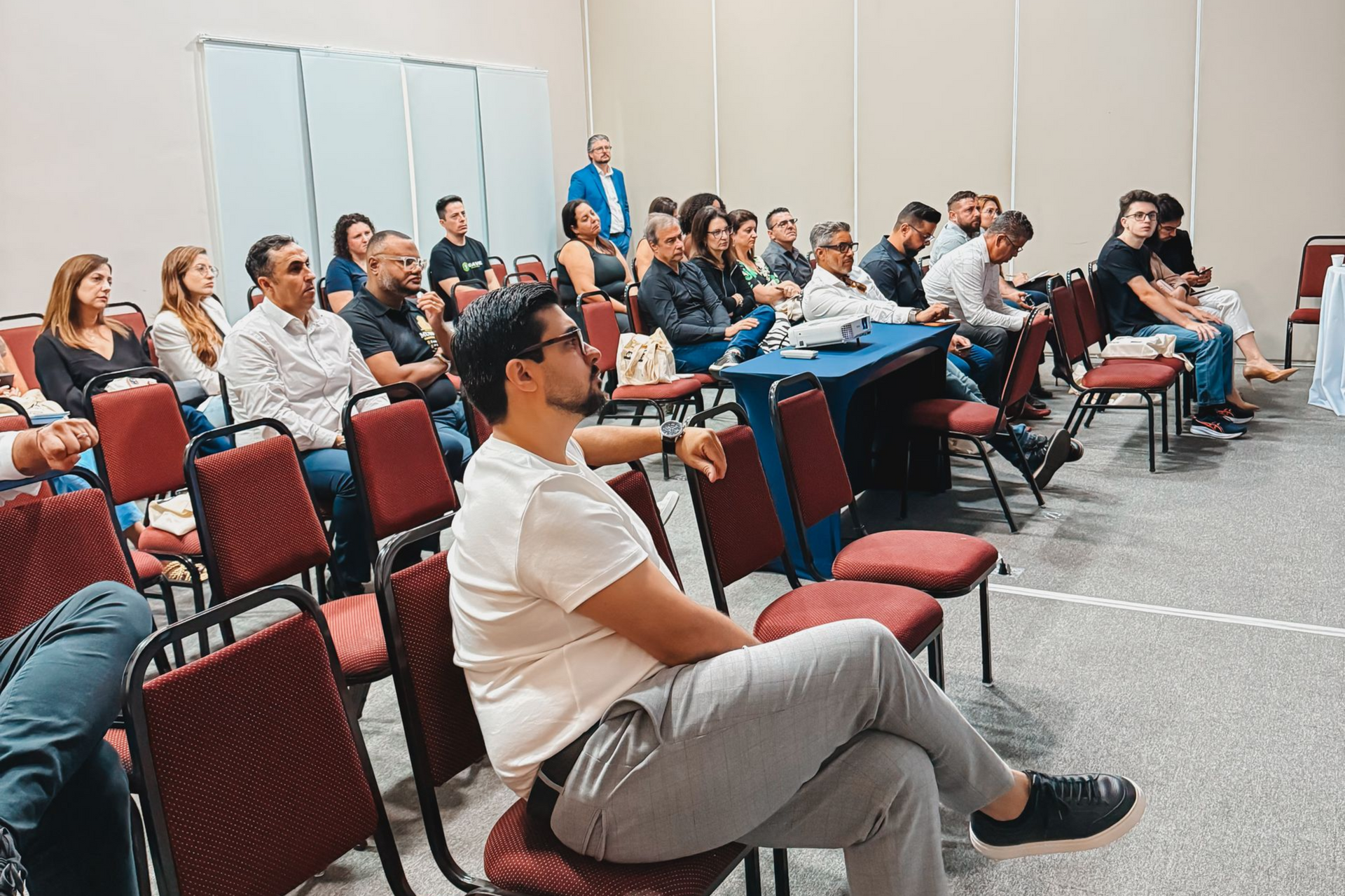 Audience seated in a conference room, listening to a presentation.