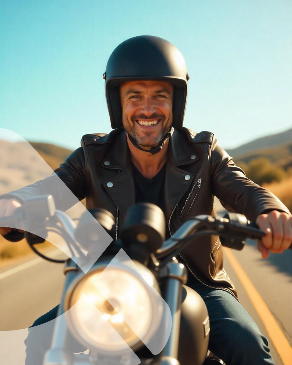Motociclista de capacete preto e jaqueta de couro pilotando em uma estrada ensolarada no deserto, sorrindo para a câmera.