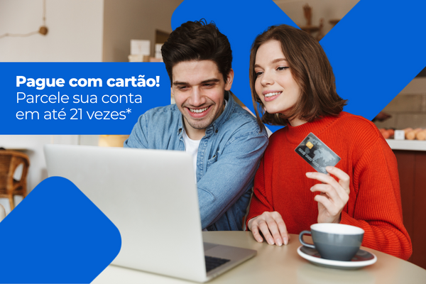 Casal sorrindo usando notebook em café, com cartão e texto promocional sobre parcelamento em até 21 vezes.