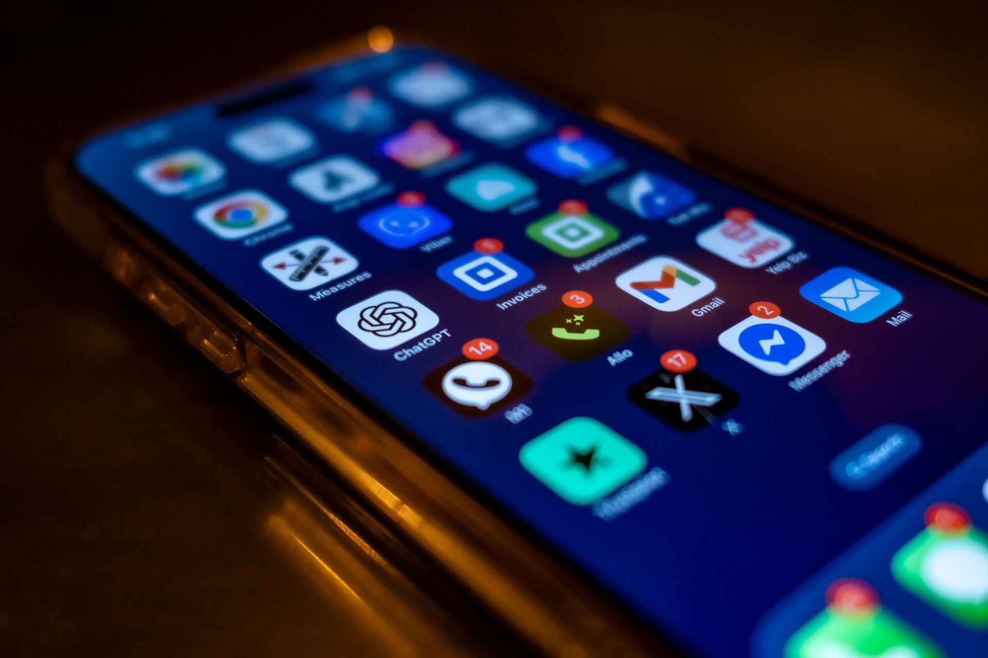 Tela de smartphone exibindo uma grade de ícones coloridos de aplicativos em um ambiente com pouca luz.