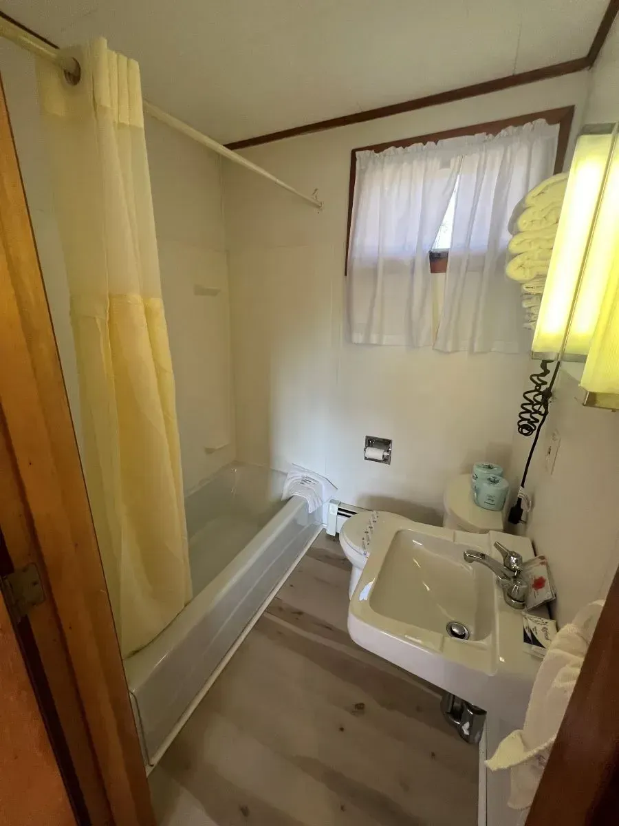 A bathroom with a sink , tub , toilet and window.