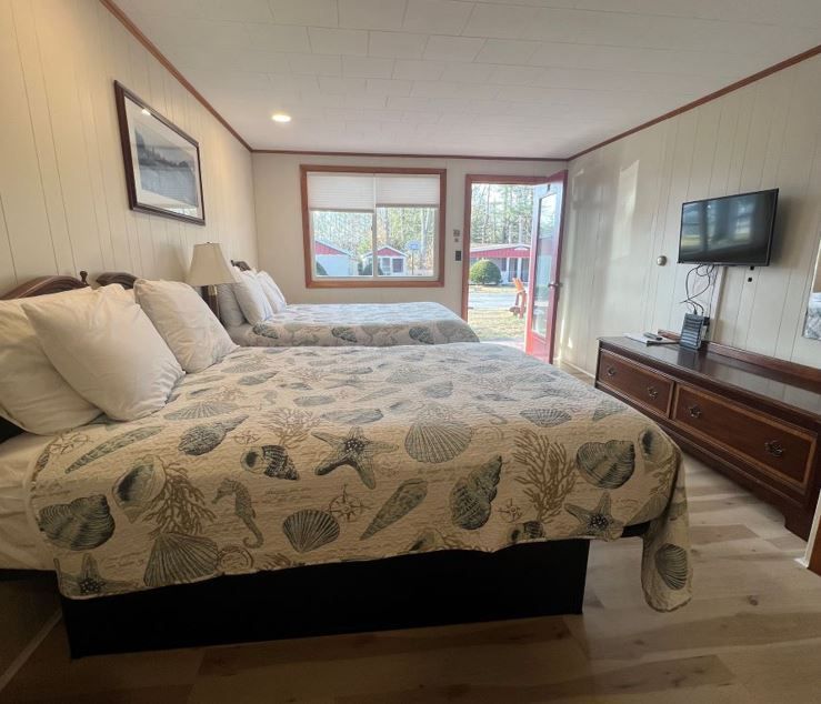 A hotel room with two beds and a flat screen tv.