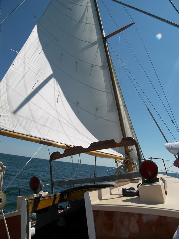A sailboat with a white sail is in the ocean
