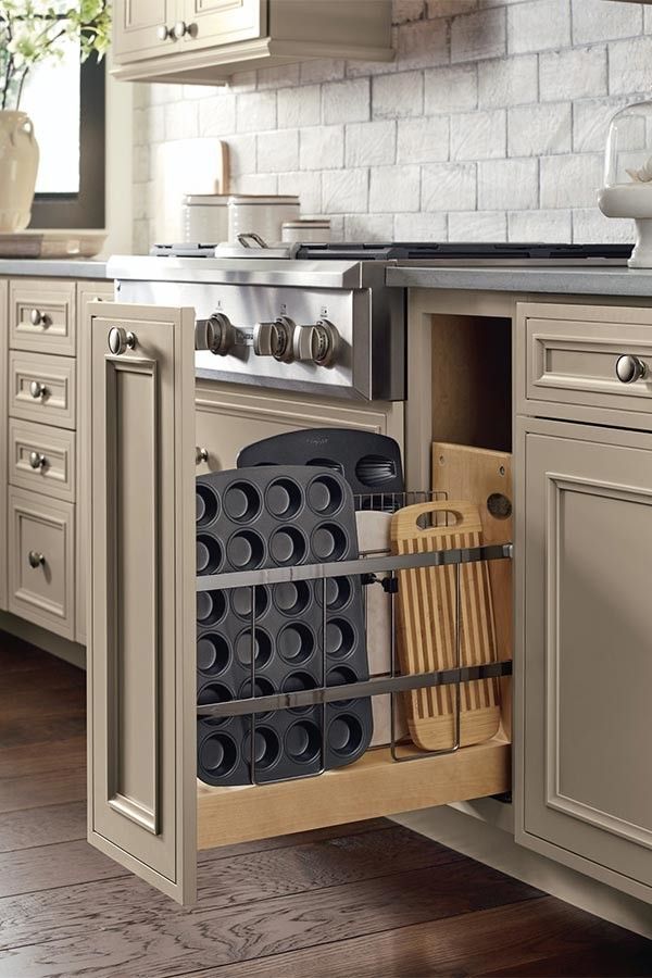 A kitchen with a pull out drawer filled with utensils and a stove.