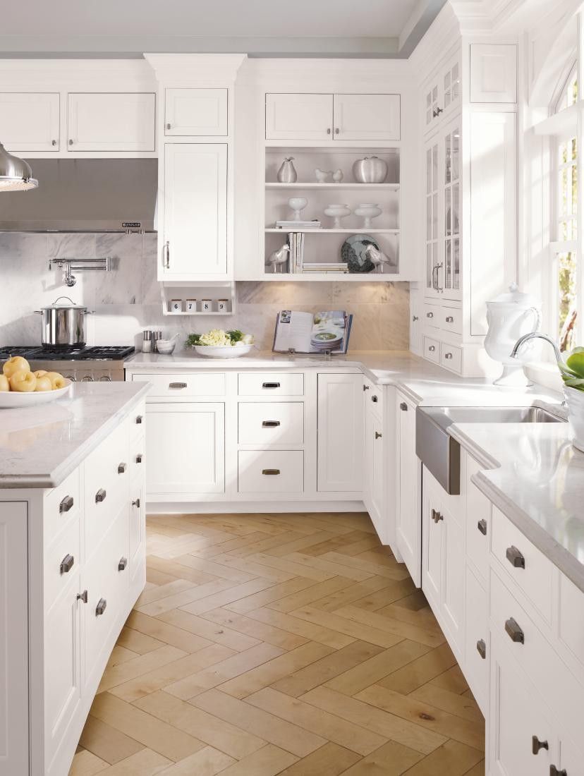 A kitchen with white cabinets and a wooden floor