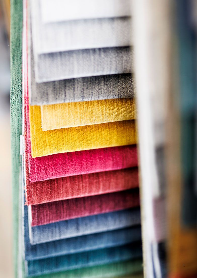 A stack of fabric swatches in a range of colors including yellow, pink, blue, green, and gray, arranged in a fan.