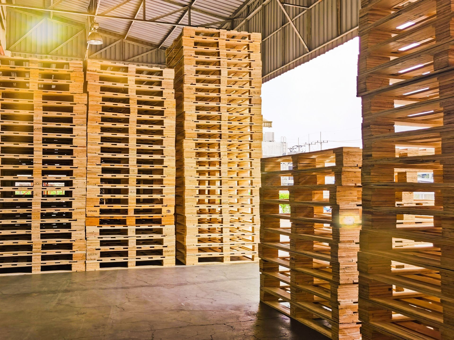 A warehouse filled with lots of wooden pallets stacked on top of each other.