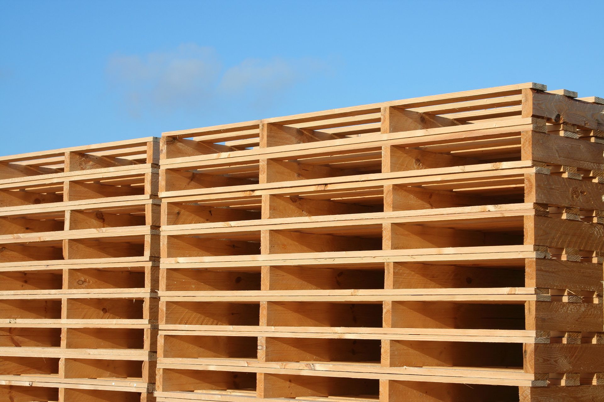 A pile of wooden pallets stacked on top of each other in a warehouse.