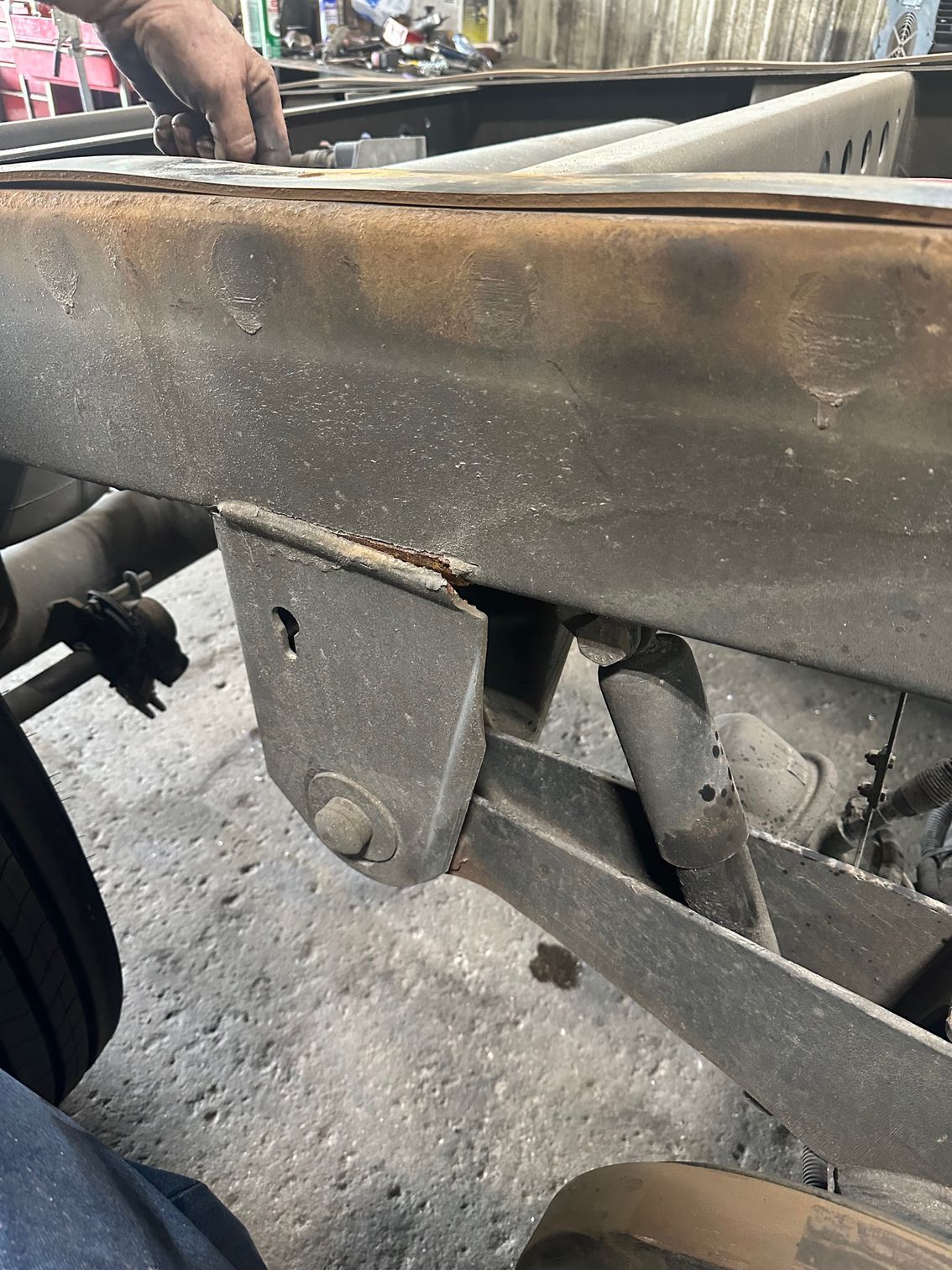 Close-up of a vehicle chassis frame with a suspension mounting bracket and shock absorber attached to the metal rail.