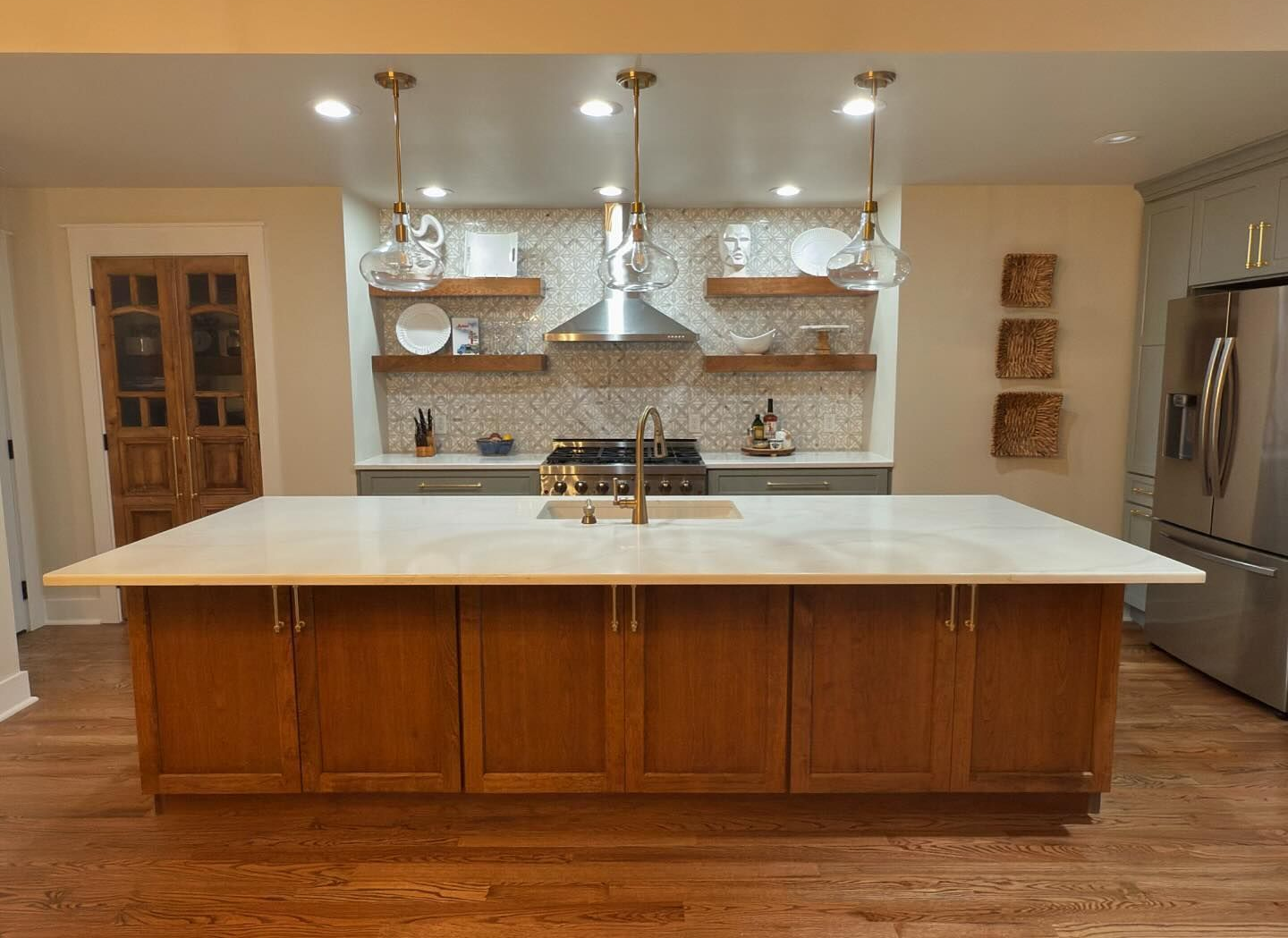 White kitchen cabinets with stainless steel hood, gas cooktop, and gold hardware.