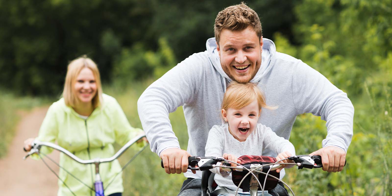A man is riding a bike with a child on the back.