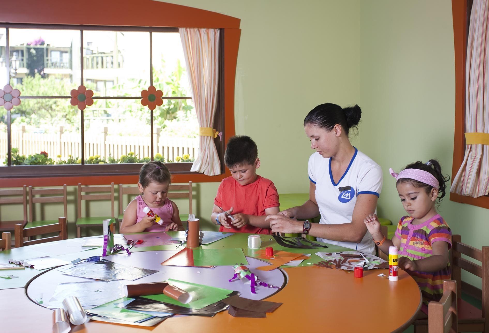 Une femme est assise à une table avec trois enfants.