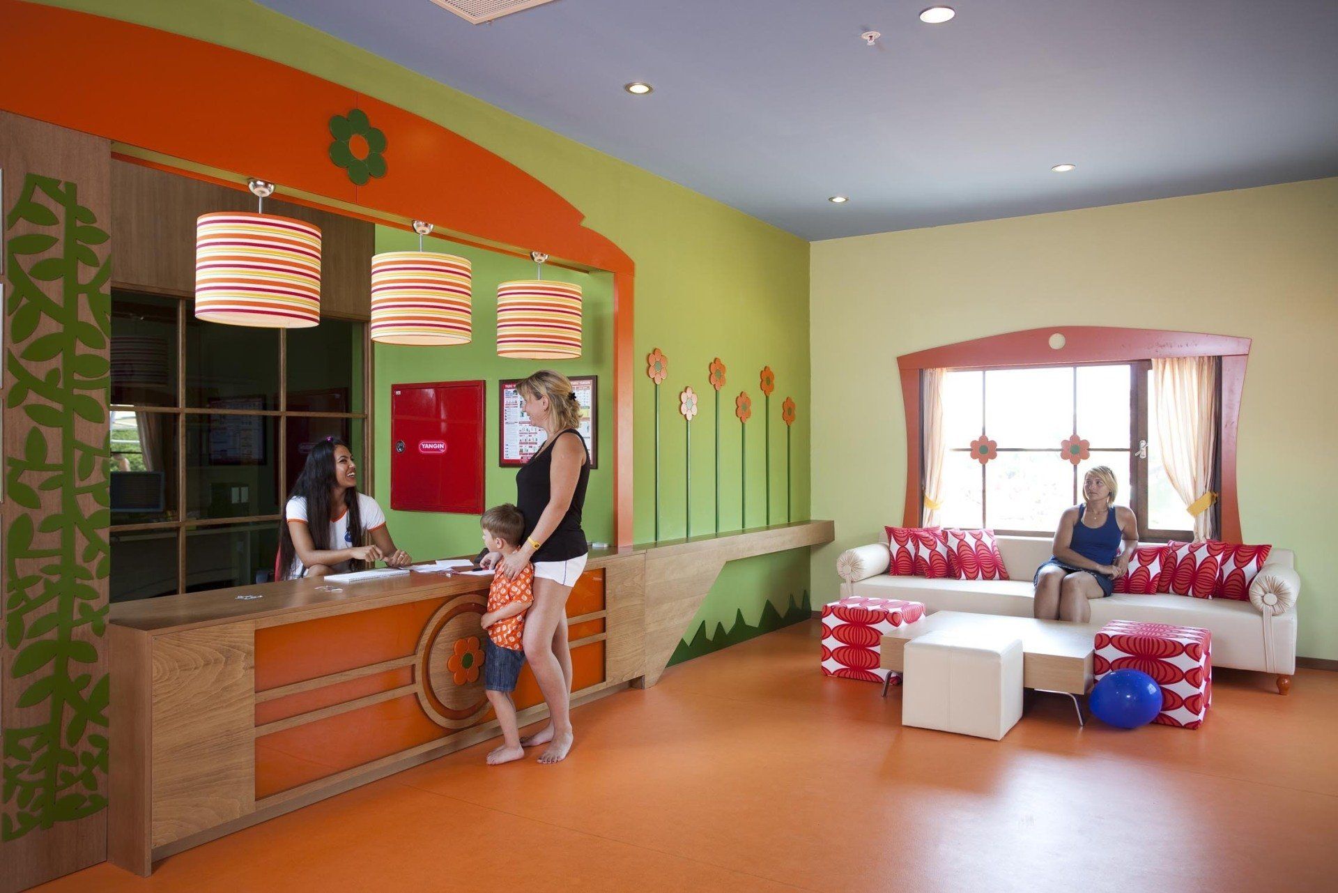 Une femme et un enfant se tiennent devant un comptoir dans une pièce colorée.