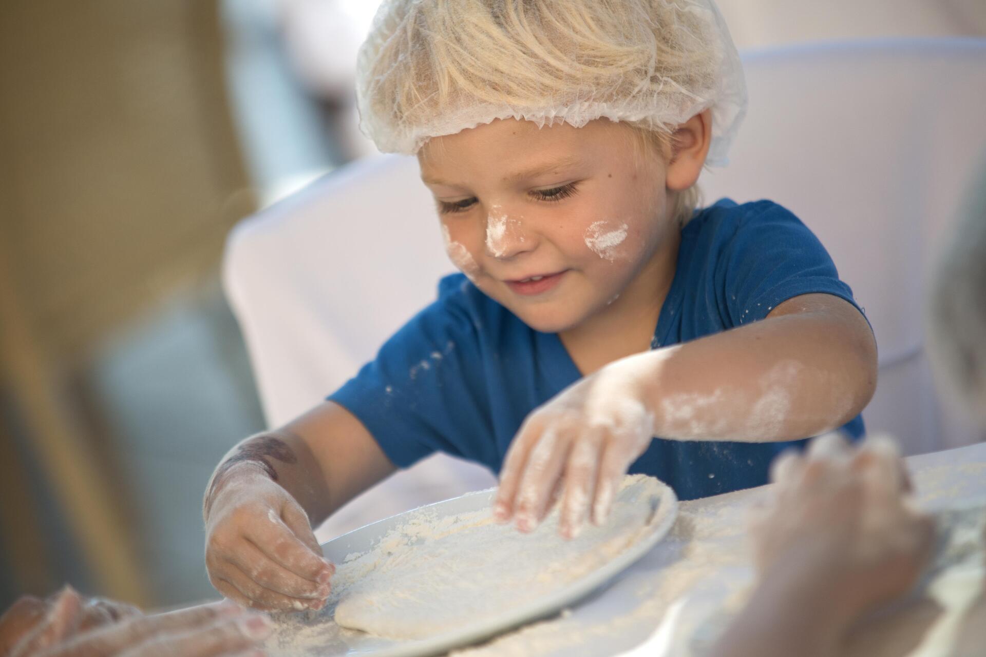 A little boy is playing with flour on a plate.
