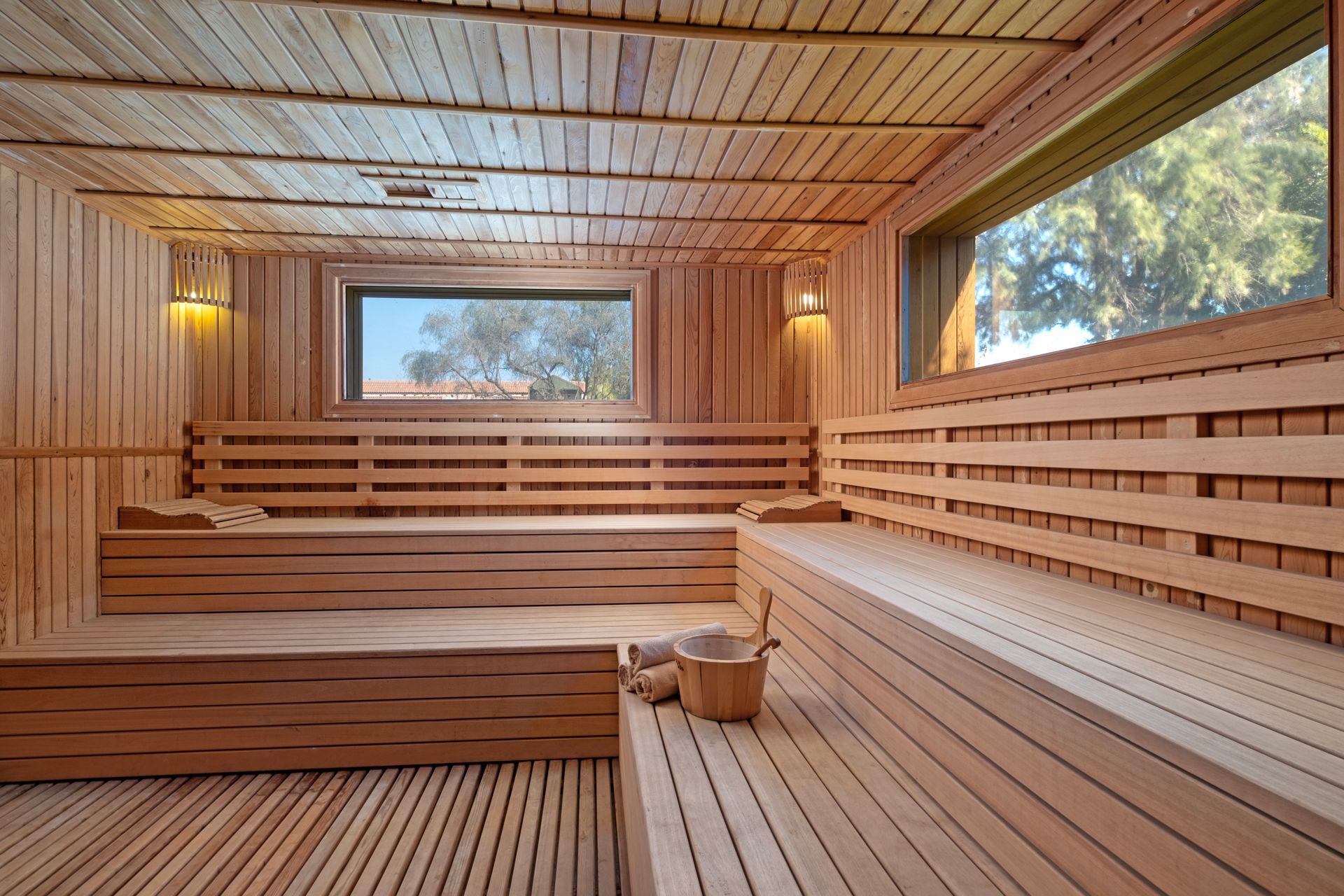 A wooden sauna with a lot of benches and a window.