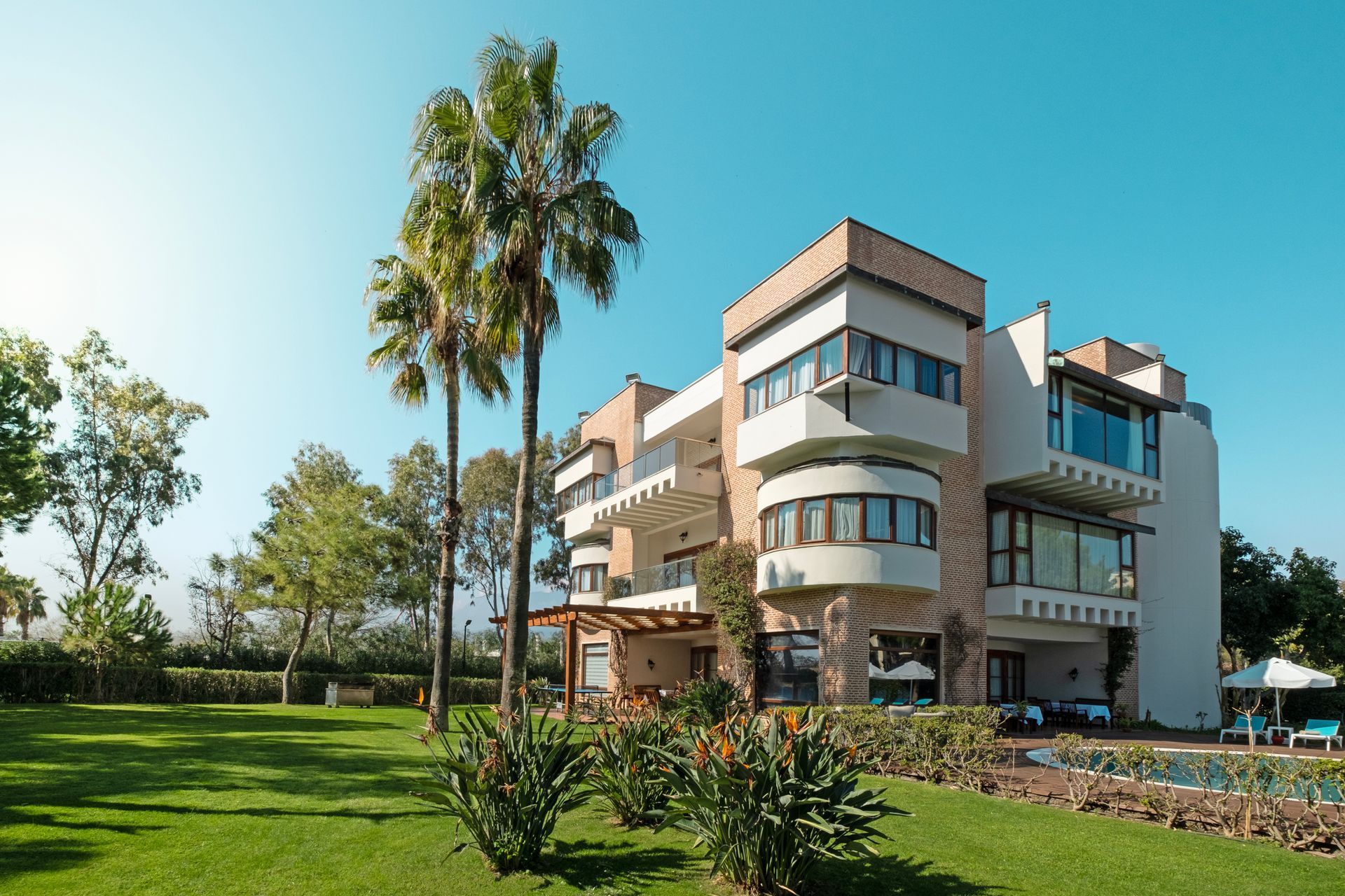 A large house with a lot of windows and palm trees in front of it.