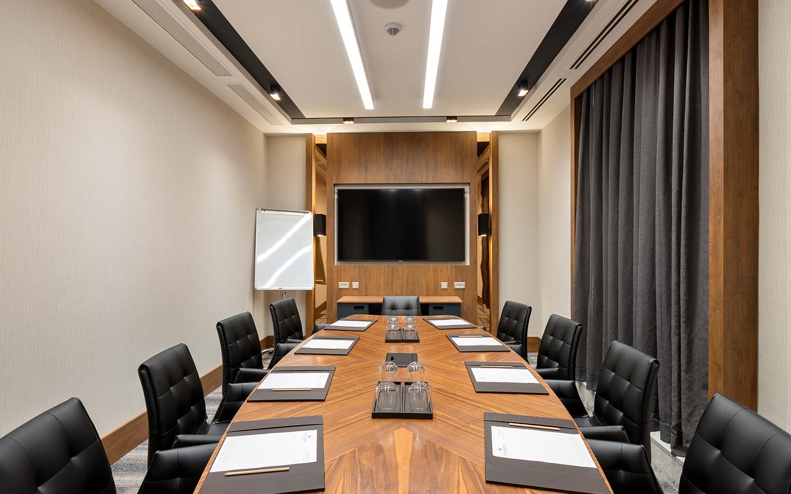 Une salle de conférence avec une longue table en bois et des chaises noires.