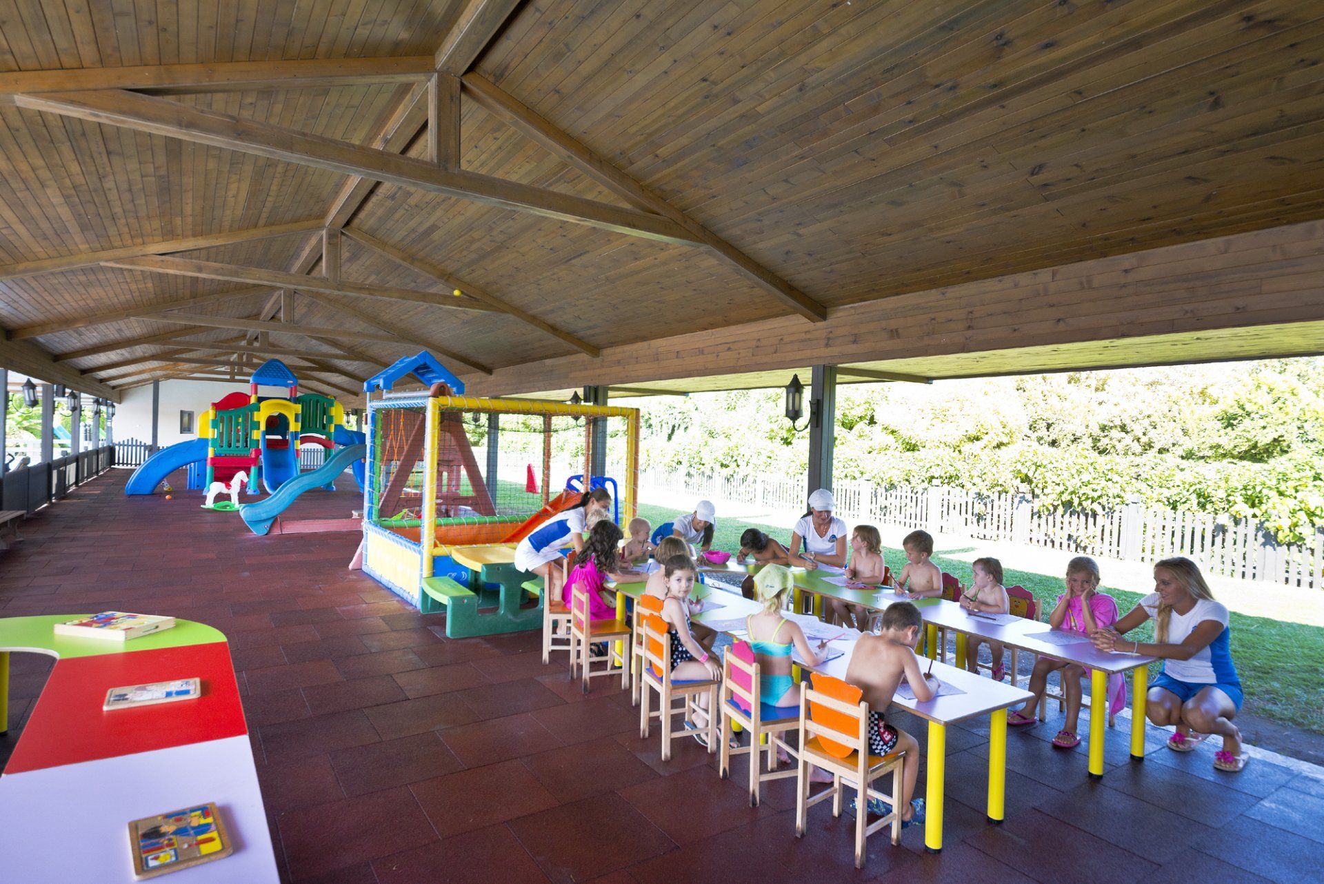 A group of children are sitting at tables in a playground.