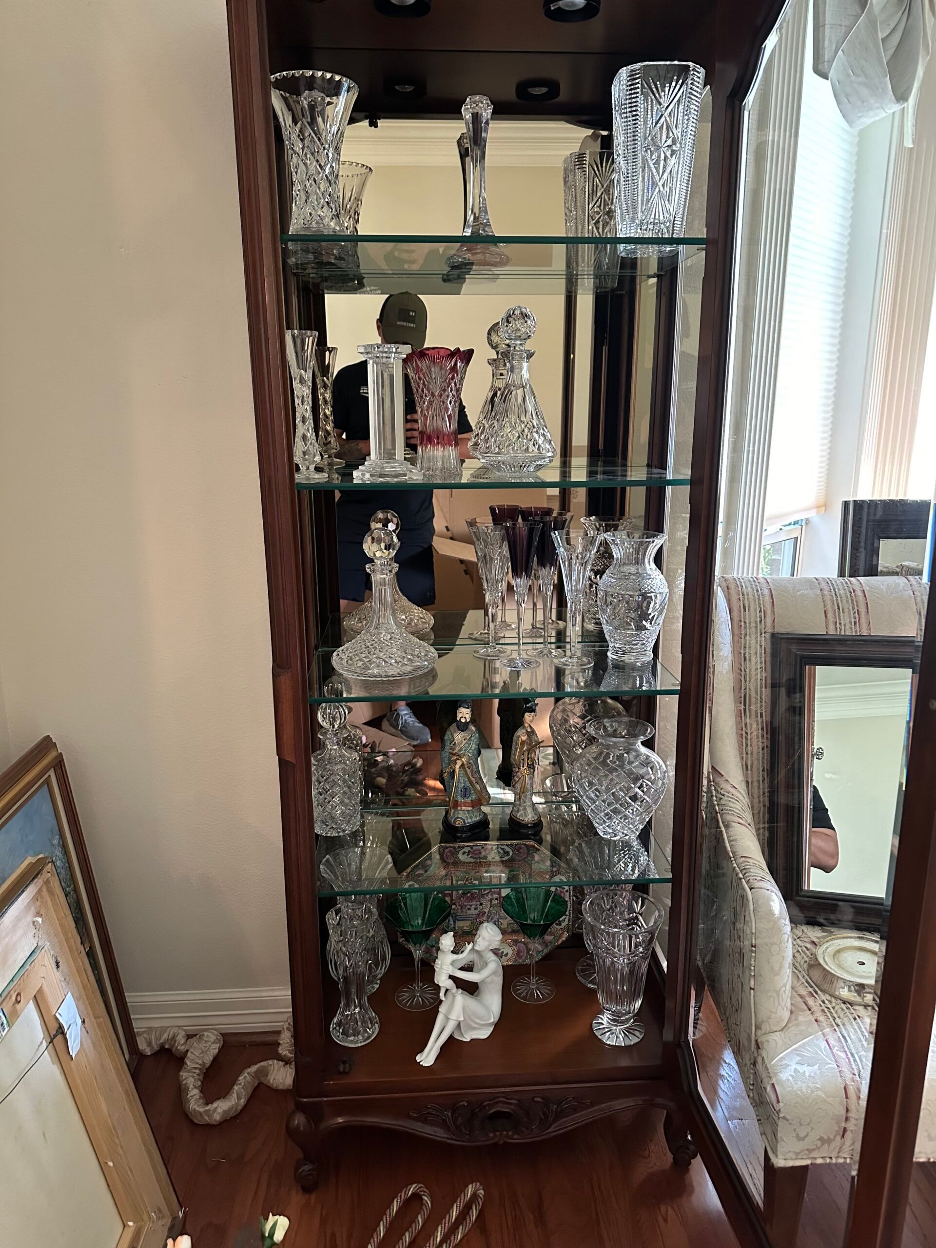 Crystal decanters, vases and figurines on the glass shelves of a curio cabinet