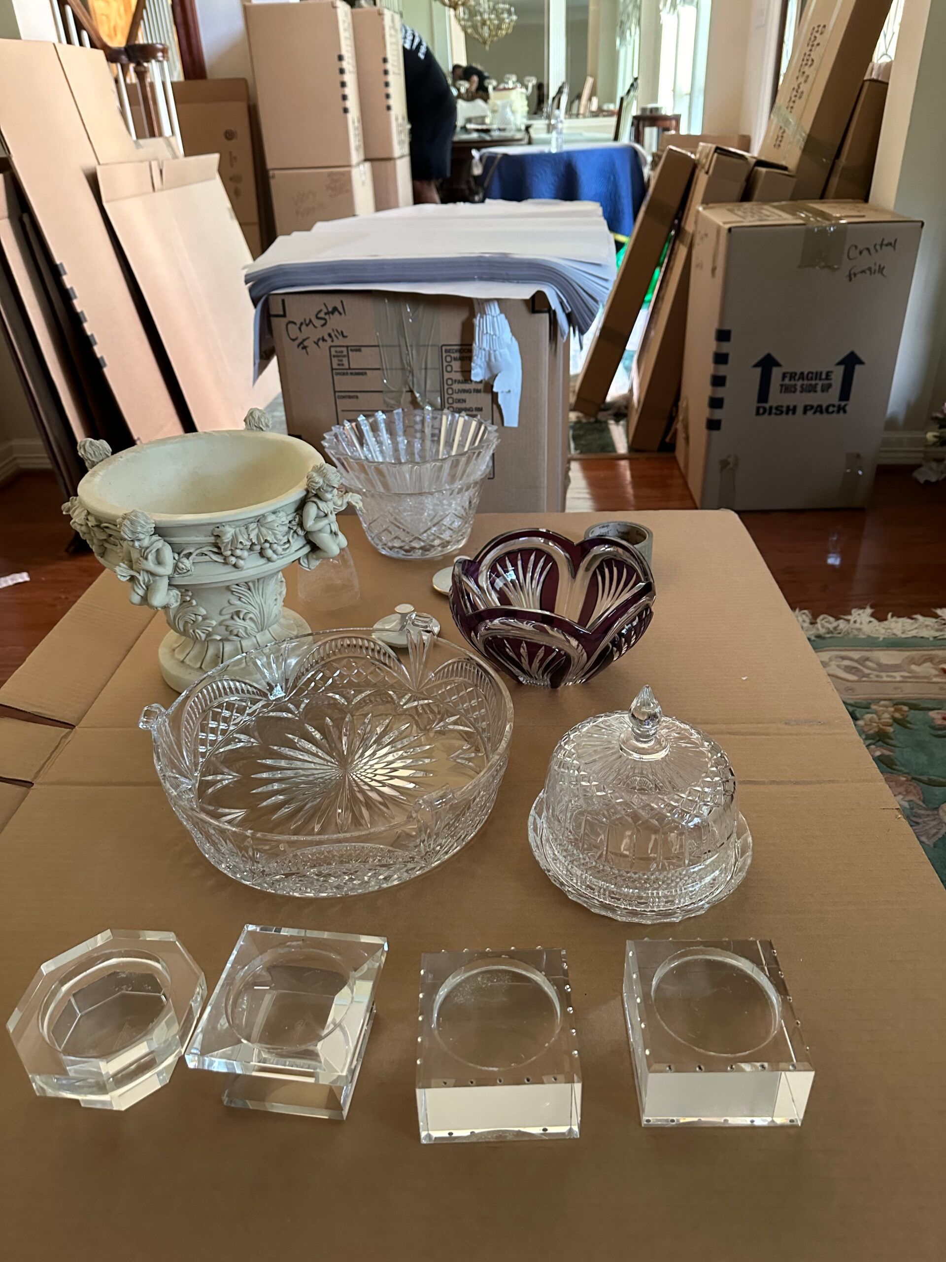 Crystal bowls and glassware set out on a moving box, with more boxes stacked behind