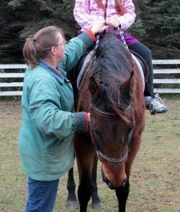A woman is helping a young girl ride a horse