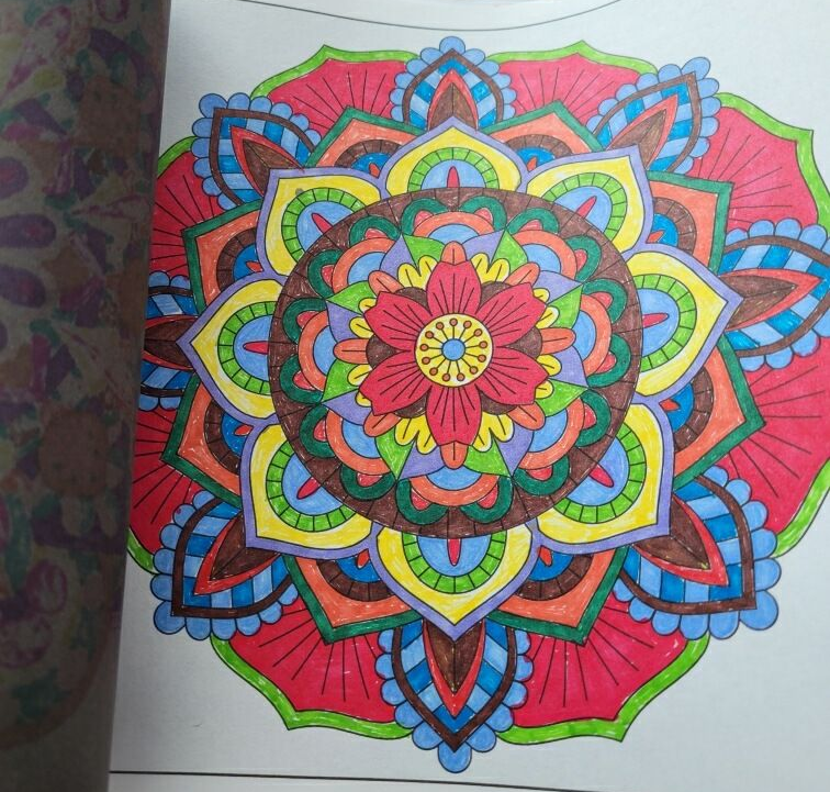 A vibrantly colored, symmetrical mandala design with circular floral patterns in red, yellow, blue, green, and orange.