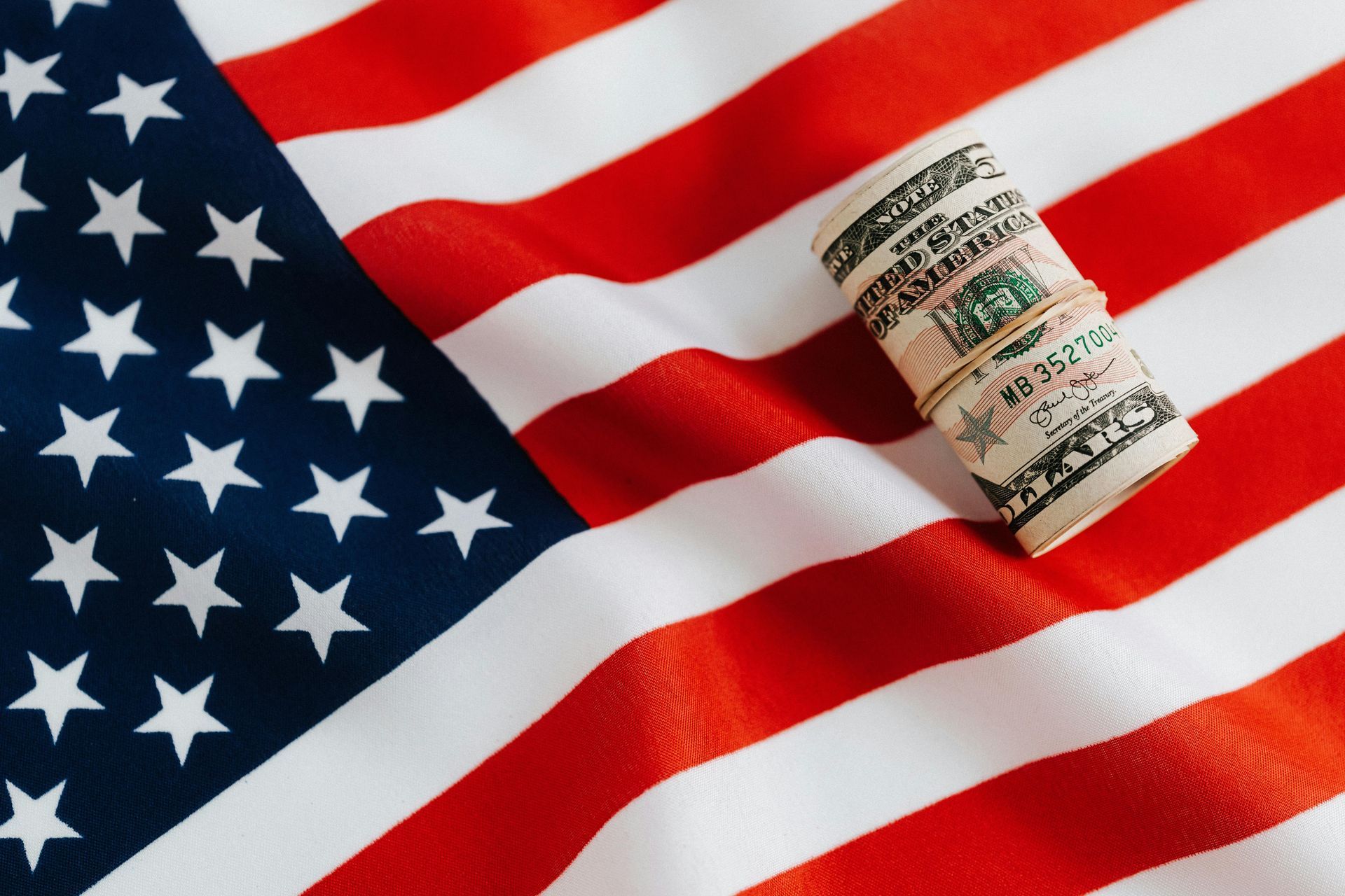 Close up of a US flag with a roll of money sitting on it