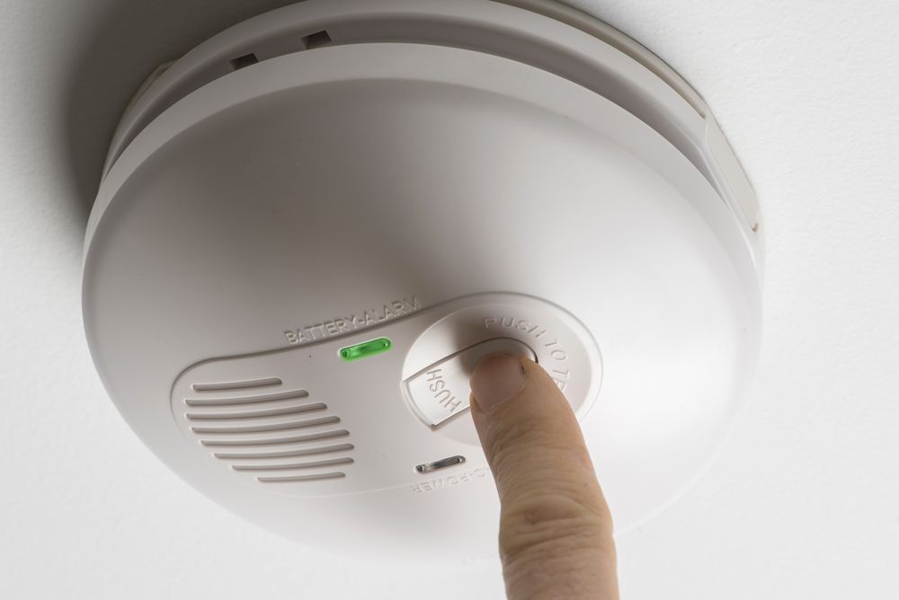 Person Presses the Button on the Smoke Detector — Hazlec Services Pty Ltd in Rockhampton, QLD