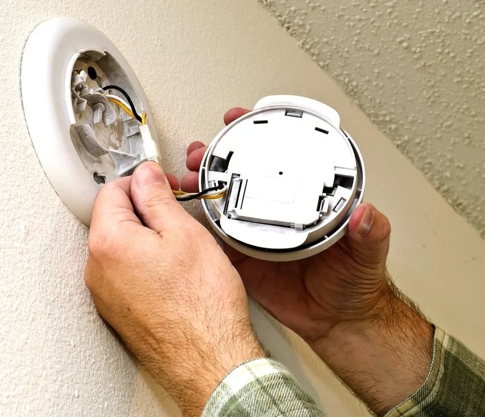 Person Installing a Smoke Detector on a Wall — Hazlec Services Pty Ltd in Yeppoon, QLD
