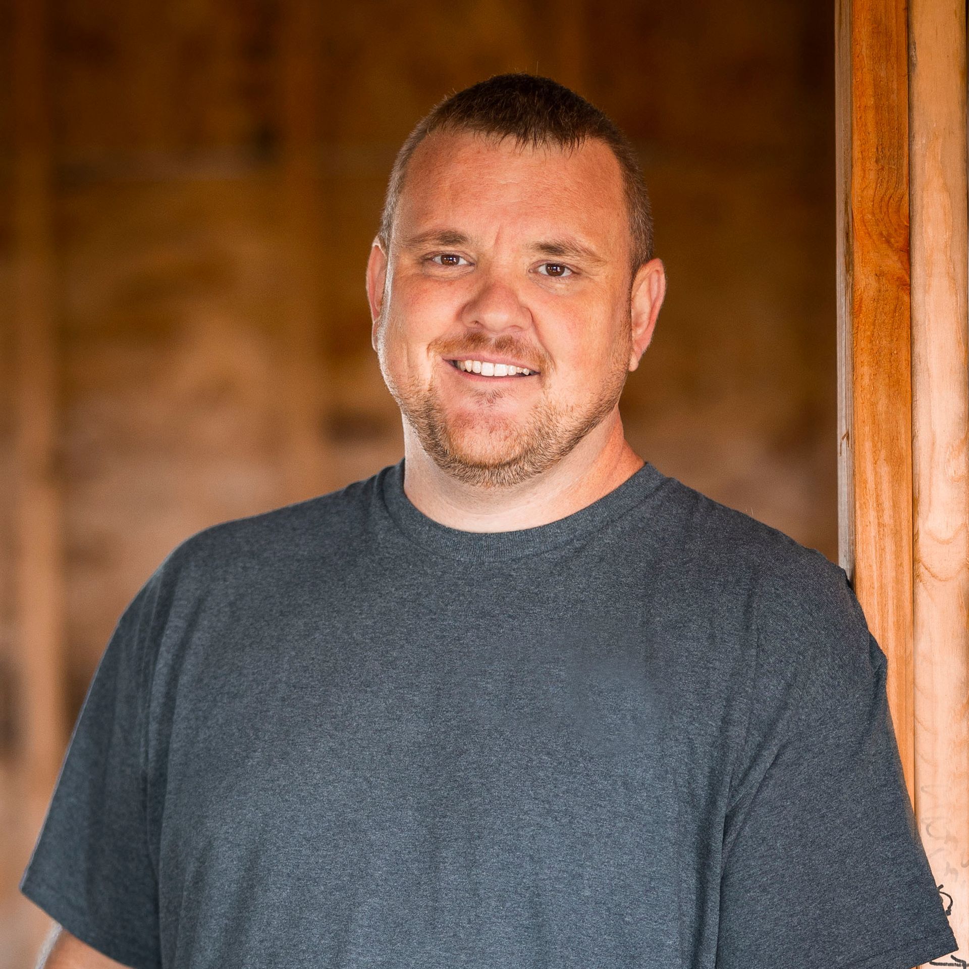 A man with a beard is wearing a blue shirt and smiling for the camera.