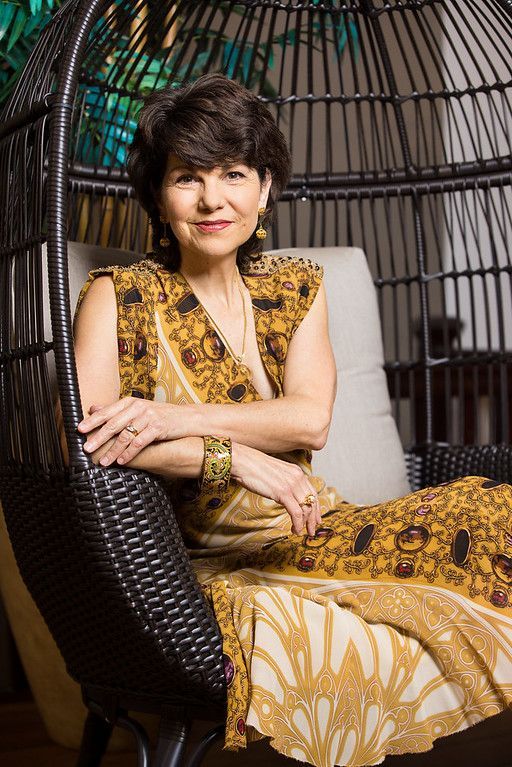 A woman in a yellow dress is sitting in a wicker chair