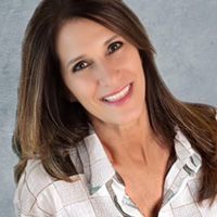 A woman in a plaid shirt is smiling for the camera.