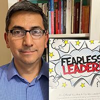 A man wearing glasses is holding a sign that says `` fearless leaders ''.