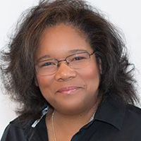 A woman wearing glasses and a black shirt is smiling for the camera.
