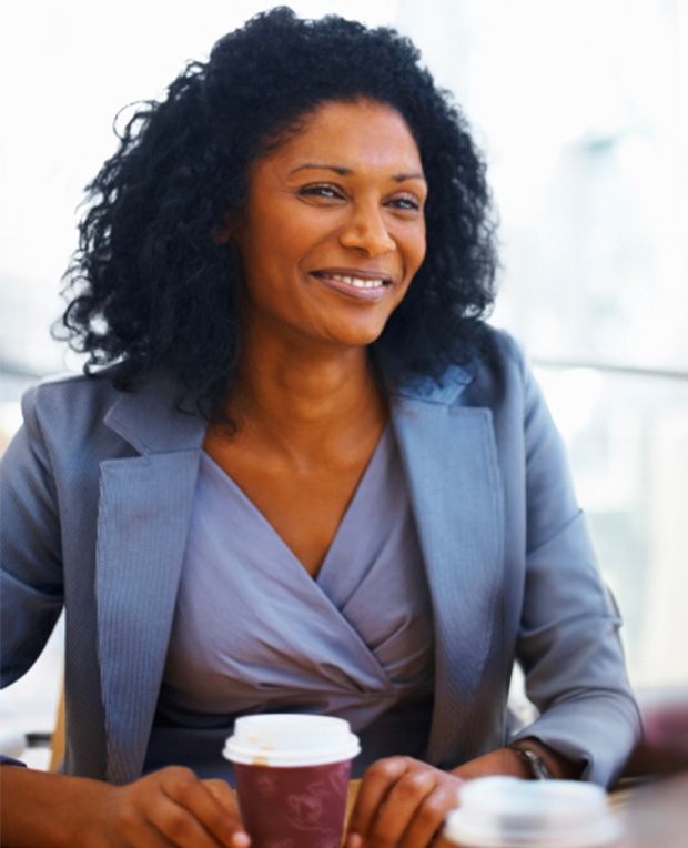 A woman is sitting at a table holding a cup of coffee