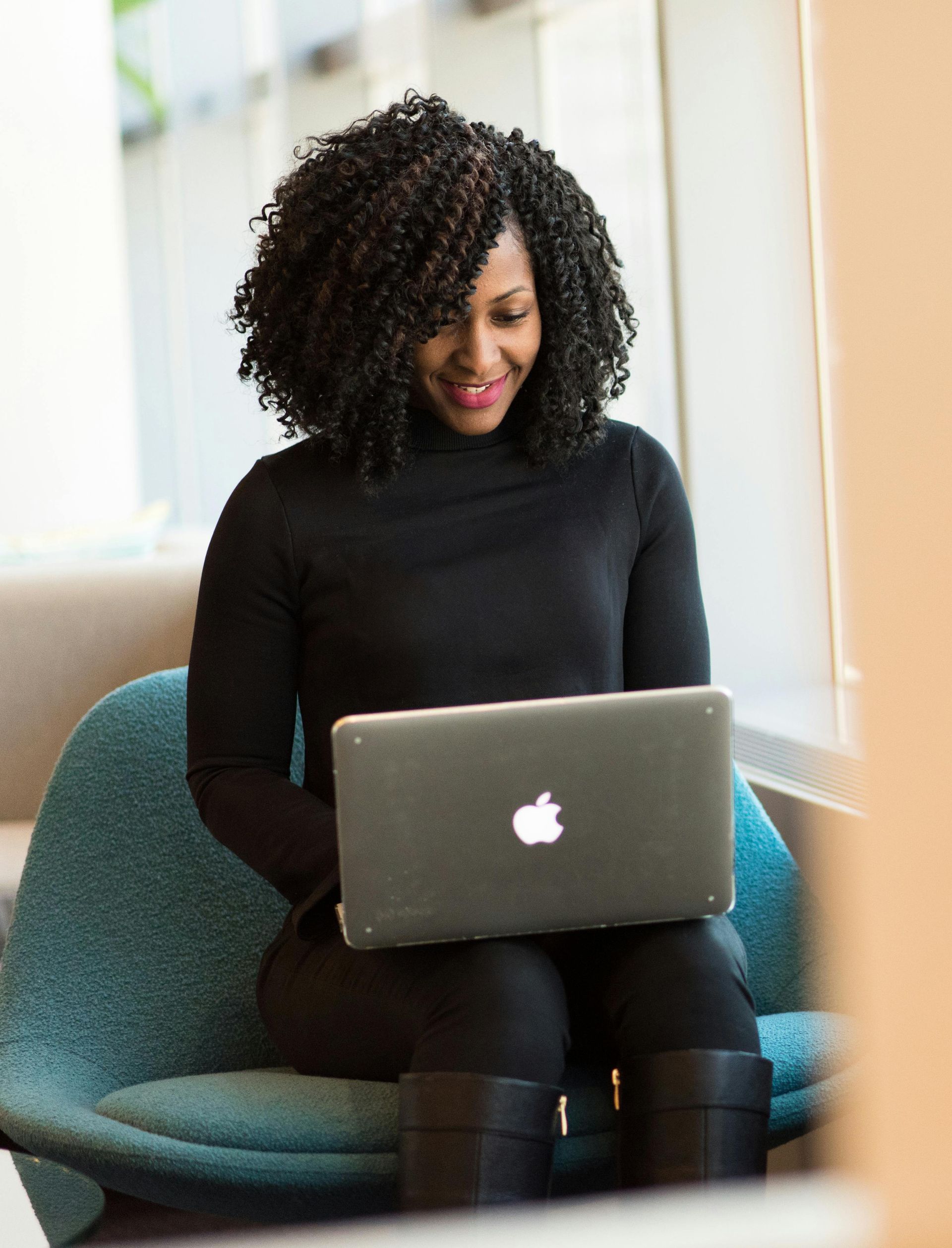 A woman is sitting in a chair using an apple laptop