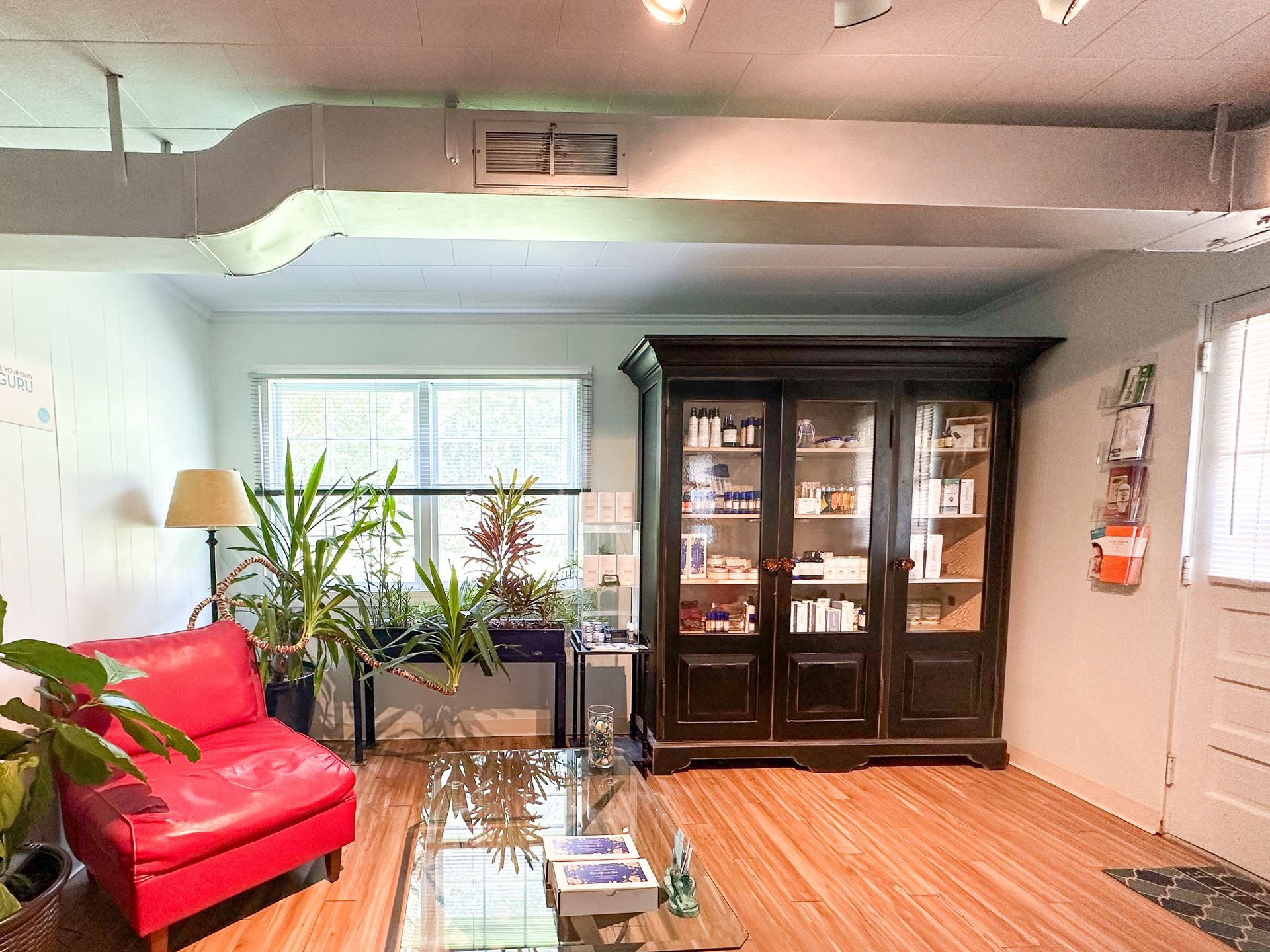 A living room with a red chair and a glass coffee table.