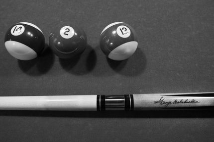 Three billiard balls with a white cue stick on a dark felt pool table.
