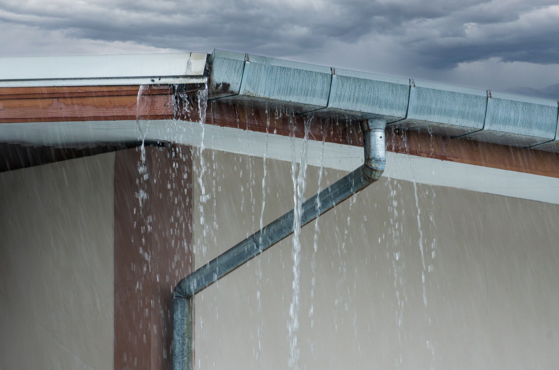 Rainwater leaking from a roof gutter onto a building wall